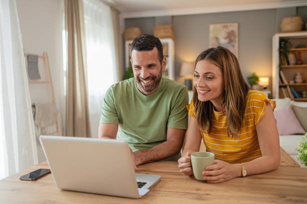 Shot of an adorable smiling young couple using laptop together at home.